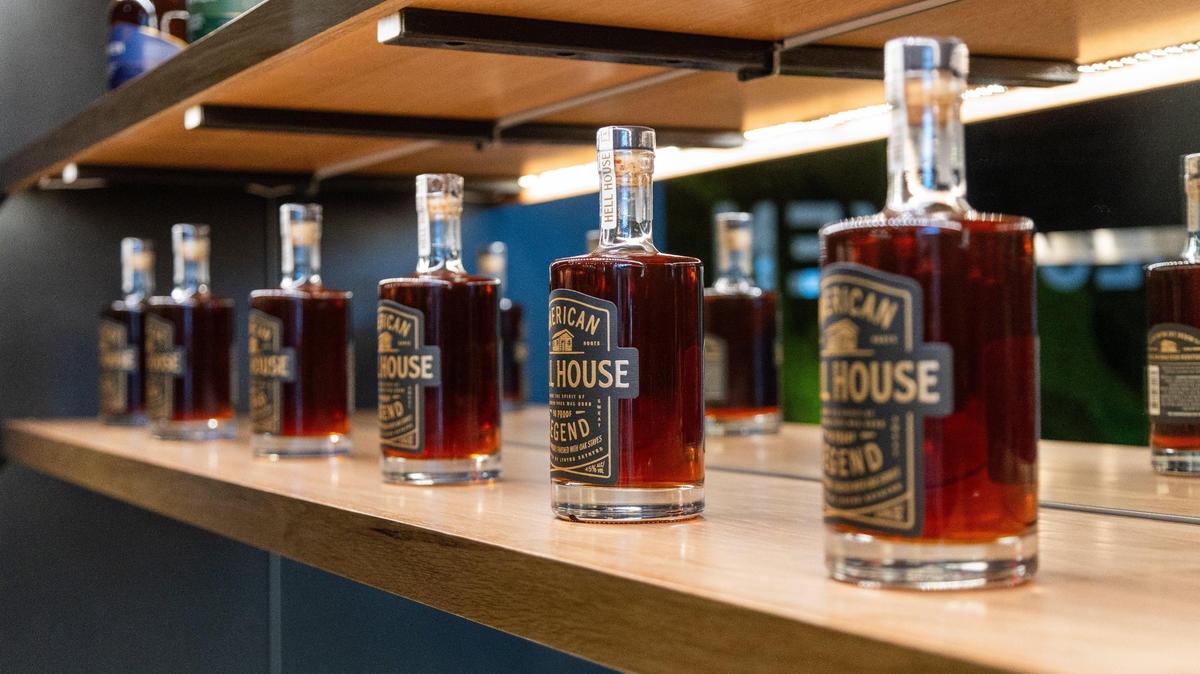 Several Hell House bottles line a shelf within Bespoken Spirits tasting room In Greyline Station on West Loudon Avenue, March 20, 2024.