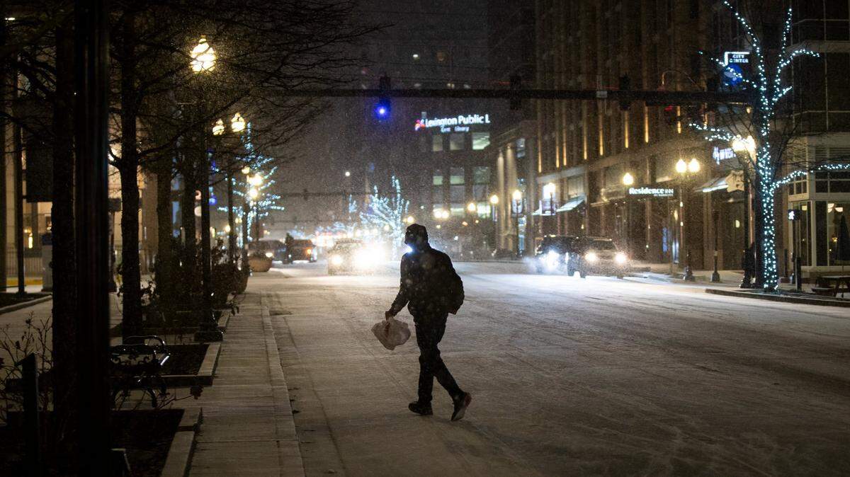 A pedestrian walks through downtown Lexington, Ky., as snow fell on Jan. 15, 2024, and into the next morning.