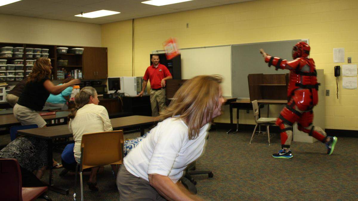 At Caldwell County school Aug. 2, 2013, trainer Richard Wright, Jr., left,  and Trevor Pervine who was playing the role of shooter, worked with teachers during Active Shooter Survival Training. The two school staff members who are standing and moving are Debbie Howton, left, and Natalie Lacy. Photo by Tonya Clevidence of the Kentucky State Police.