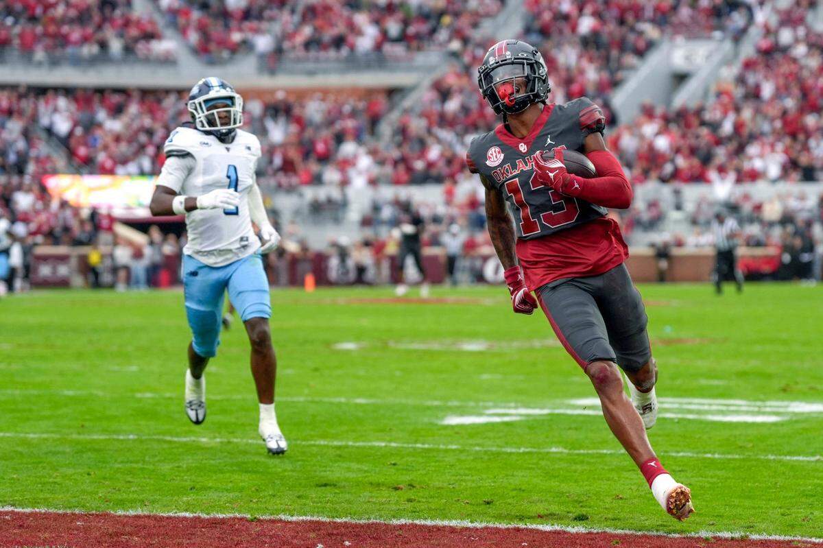 Oklahoma Sooners wide receiver J.J. Hester (13) runs after a reception to the end zone in front of Maine Black Bears defensive back Alhaji Kamara (1) to score a touchdown during a college football game between the University of Oklahoma Sooners (OU) and the Maine Black Bears at Gaylord Family - Oklahoma Memorial Stadium in Norman, Okla., Saturday, Nov. 2, 2024.