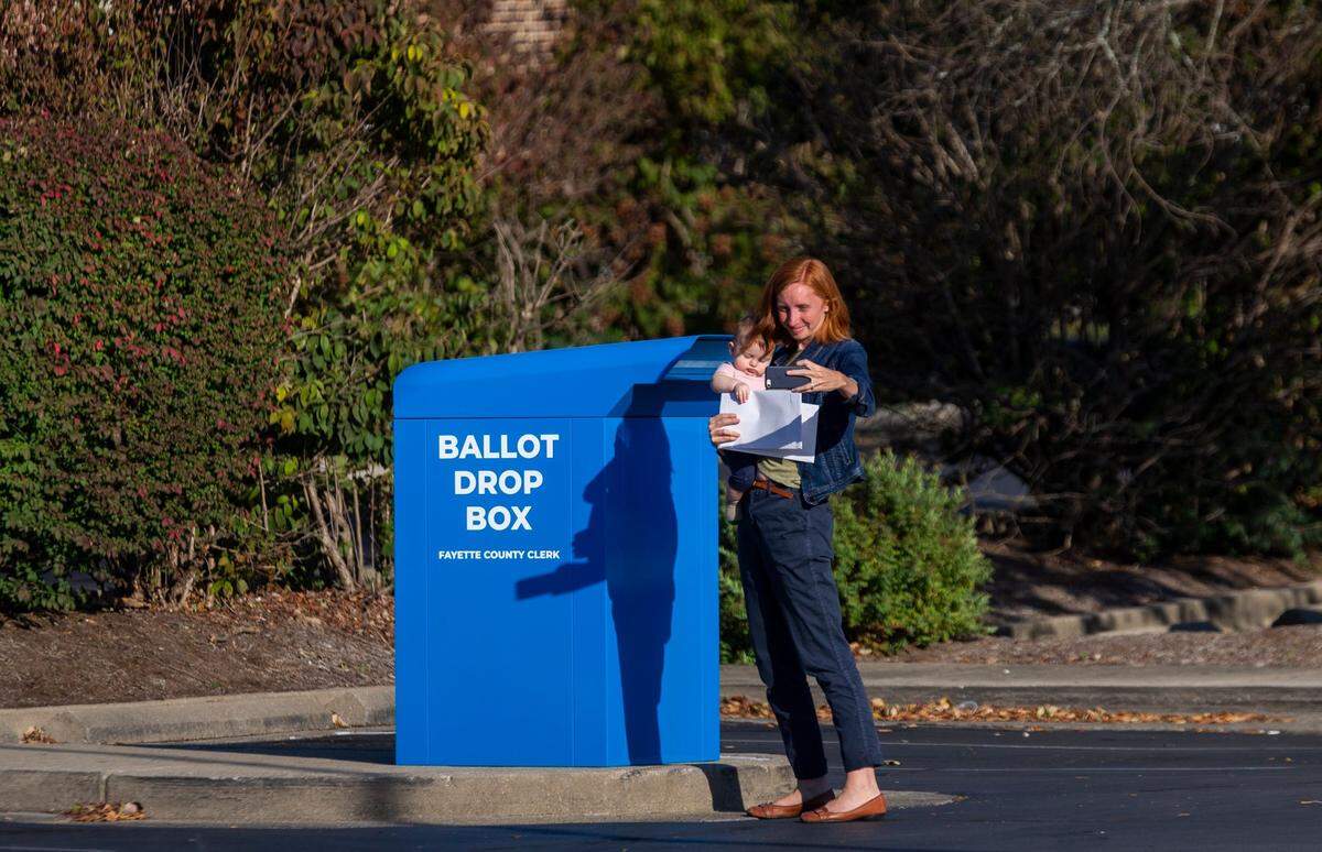 A woman takes a selfie with her child before dropping off her ballots Wednesday at a drop box outside the Tates Creek Library.
