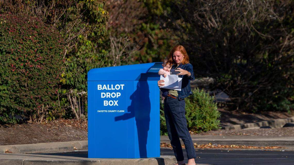 A woman takes a selfie with her child before dropping off her ballots at a ballot drop box outside the Tates Creek Branch Library in Lexington, Ky., Oct. 7, 2020.