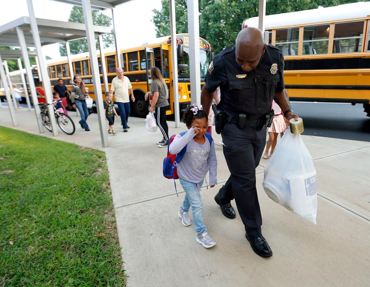 Lexington Police Chief Lawrence Weathers comforted and helped carry kindergarten student Aitana Soto’s supplies as she walked into school Wednesday morning at Cardinal Valley Elementary on the first day of school for Fayette County schools. Chief Weathers had ridden a bus to school with some of the students and stayed to greet and help other students as they arrived.
