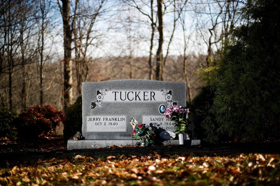 A gravestone sits behind a log cabin built as a retirement home for Jerry and Sandy Tucker at the Galilean Home in Liberty, Ky., Monday, Dec. 20, 2021. Sandy Tucker died from ovarian and colon cancer in June 2007.