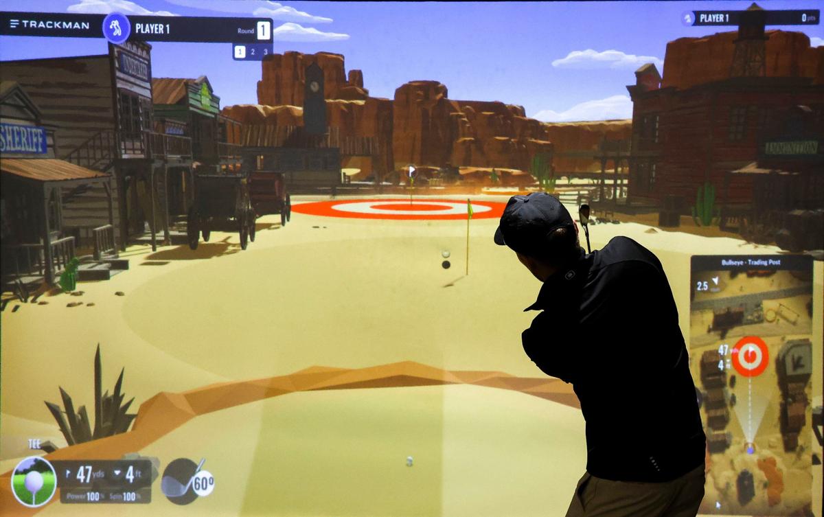 Eric Bivins, co-owner of the Sand Trap golf simulator facility, says video-like games like this one where you aim and try to hit targets are popular with large groups.