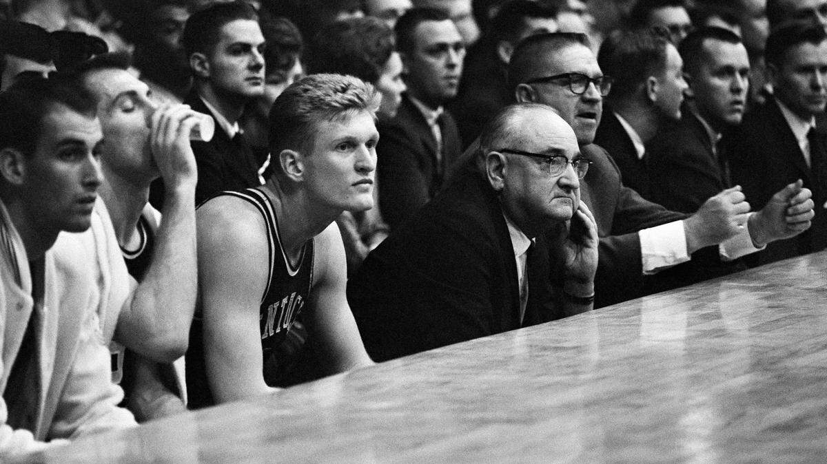 Kentucky coach Adolph Rupp scratches his chin in the waning moments of game with Ohio University as his charges go down in defeat 85-69 in the Mideast NCAA regional playoffs in Minneapolis, Minnesota on March 14, 1964. Sitting next to Rupp is All-America center Cotton Nash who was held to 10 points. Kentucky, fourth-ranked in the nation, has won four previous NCAA titles. Rupp, whose teams have won 805 games, said, This was without a doubt our worst game of the year. (AP Photo/Gene Herrick)