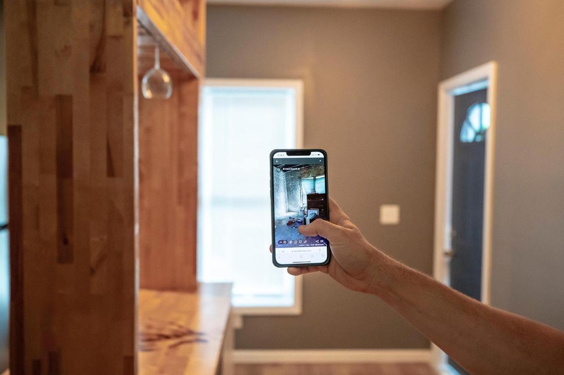 Jeff Moore, a Lexington real estate investor, holds a phone displaying a photograph taken in the same place before renovations where undertaken on a home on East Seventh Street in Lexington, Ky., on Tuesday, Aug. 30, 2022.