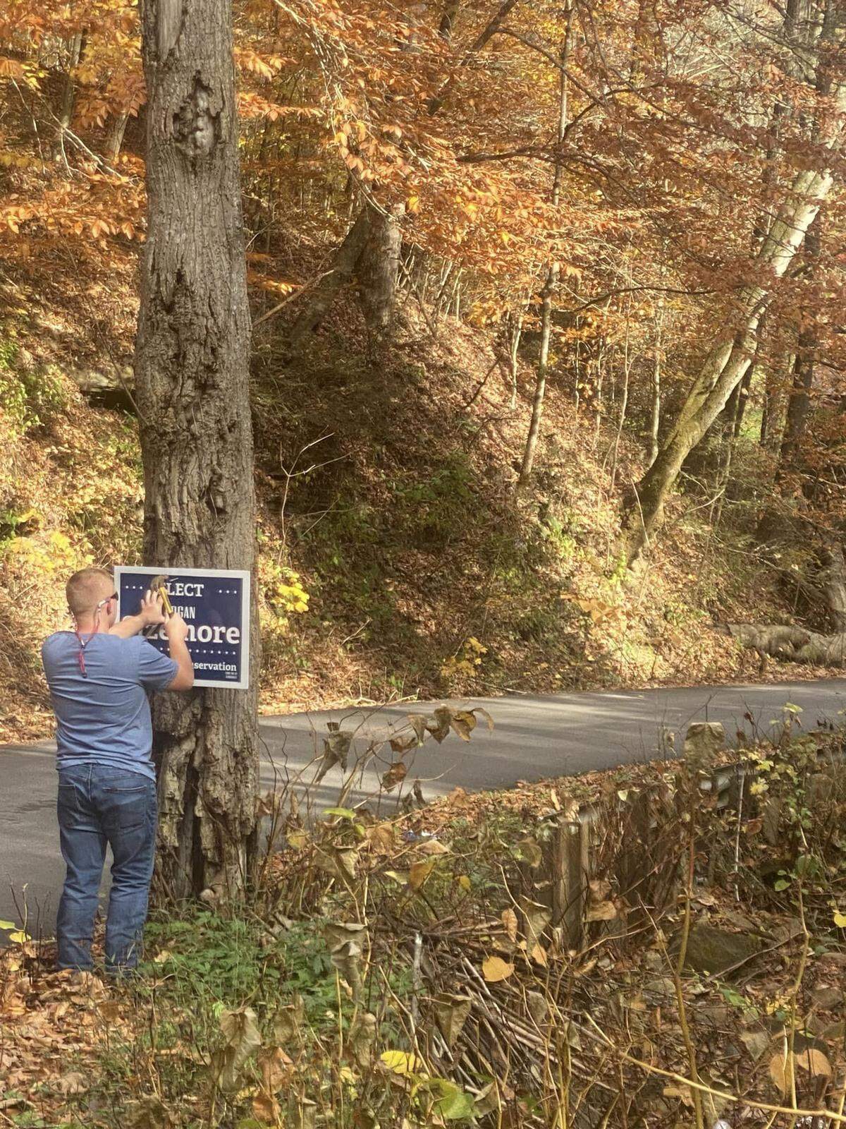 Logan Sizemore hangs a campaign sign in Leslie County, Ky.