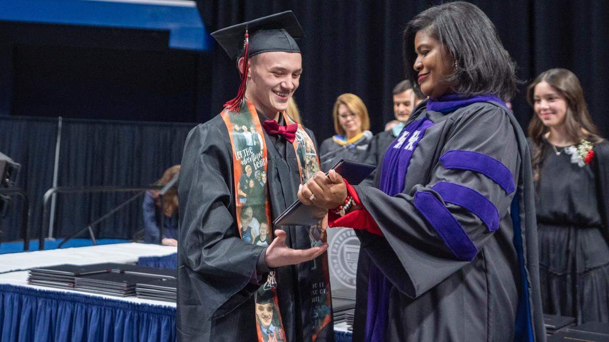 Fayette County District Judge Melissa Murphy hands a high school diploma to a juvenile treatment court graduate.