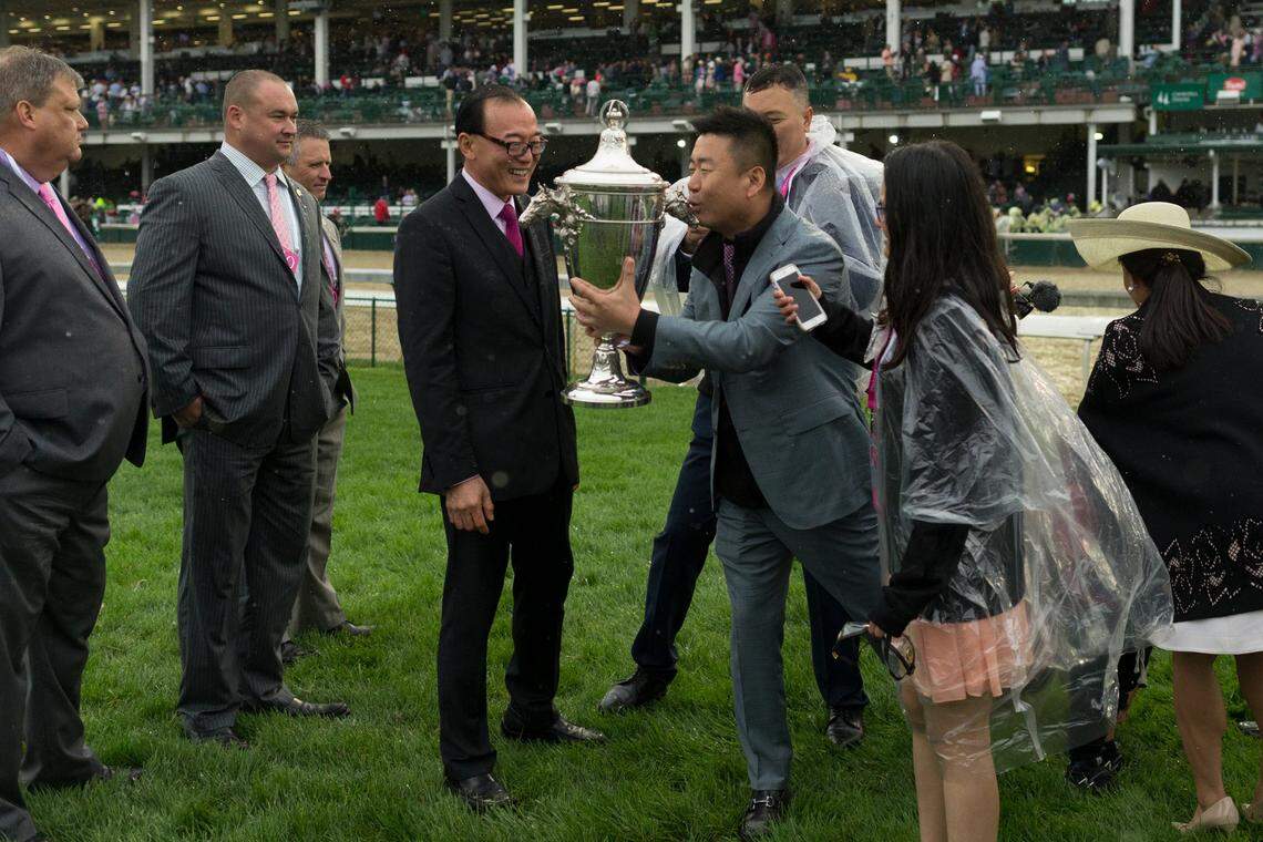 China Horse Club chairman Teo Ah Khing, center watched as other members of the club kissed the trophy after last year's Kentucky Oaks at Churchill Downs.  China Horse Club owns parts of Kentucky Derby hopefuls Audible and Justify in the 2018 Kentucky Derby.