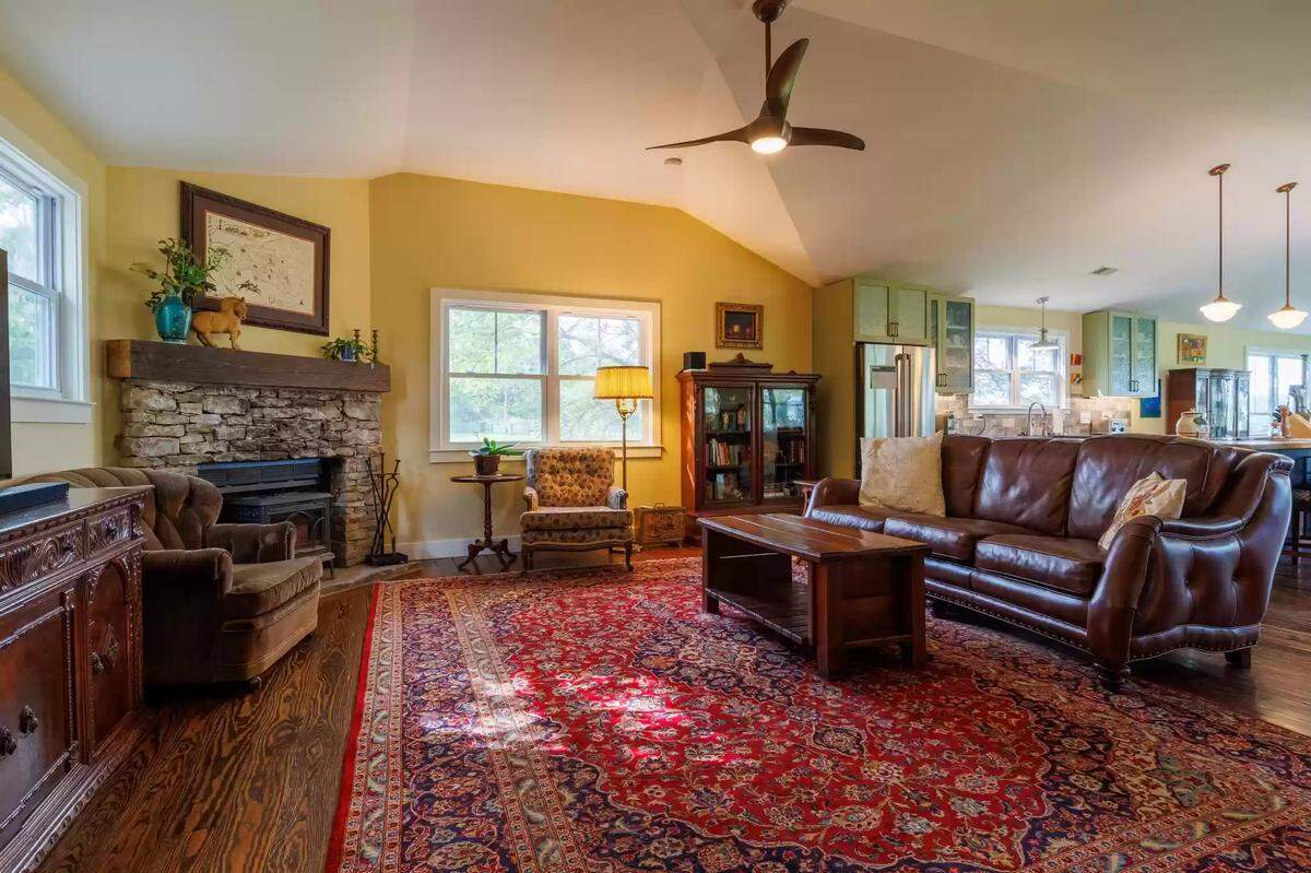 A view of the living room at 4351 Bethel Road in Lexington, KY. The living room is painted with a sunny yellow color and has a warm, hardwood floor. The room is lit by windows that let in natural light. 