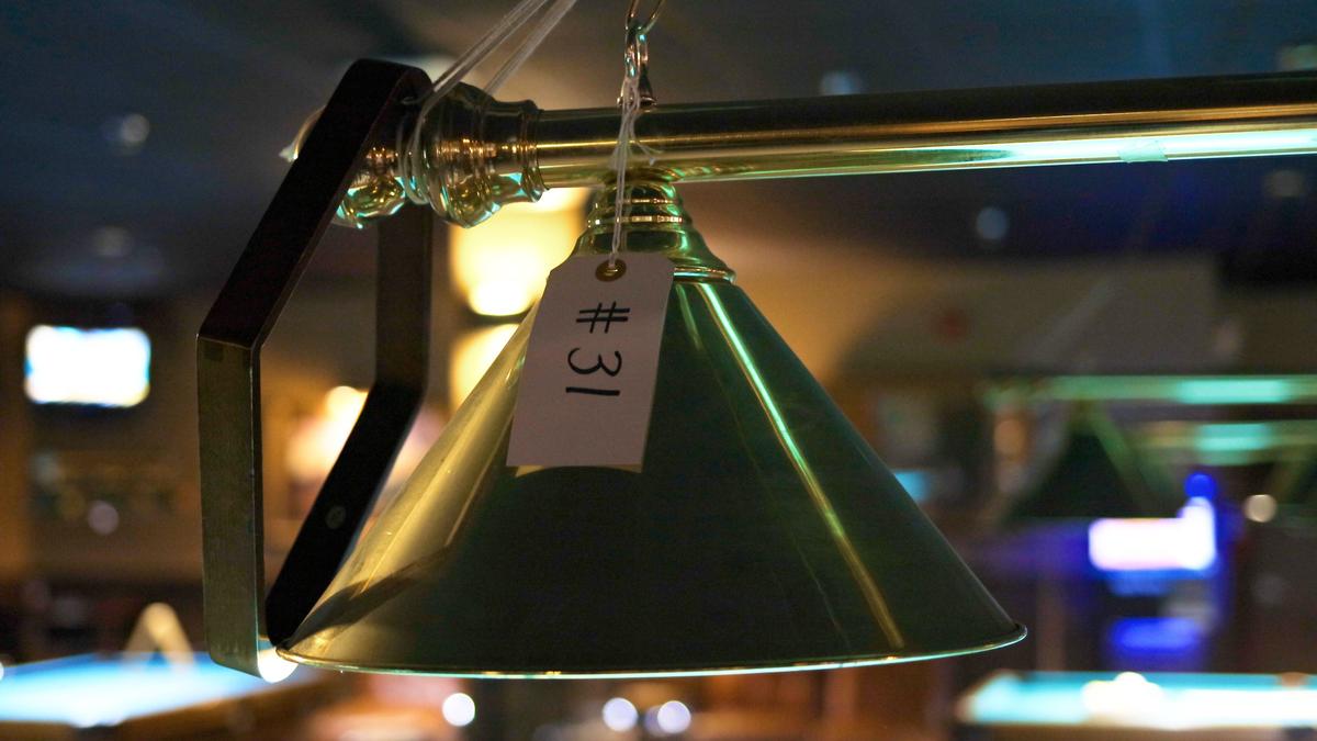 An auction tag adorns a lamp above a billiards table within Yesterday’s Billiards restaurant and bar. The restaurant will auction off equipment beginning in March.