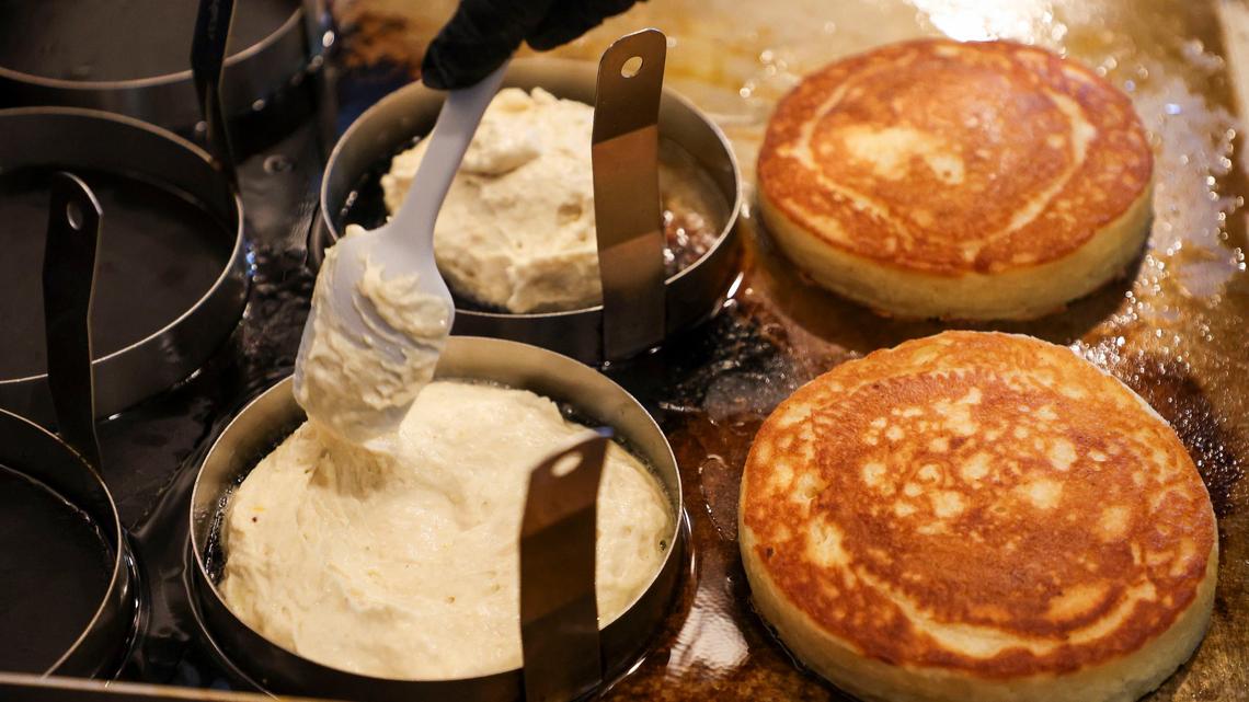 Beau’s Cafe chef and co-owner Spencer Sirles puts buttermilk pancake batter into rings, left, as another order cooks at right. The pancakes are first cooked using a six-inch-wide mold to help them rise and keep their shape. The pancakes rise to about an inch to an inch and a quarter high.