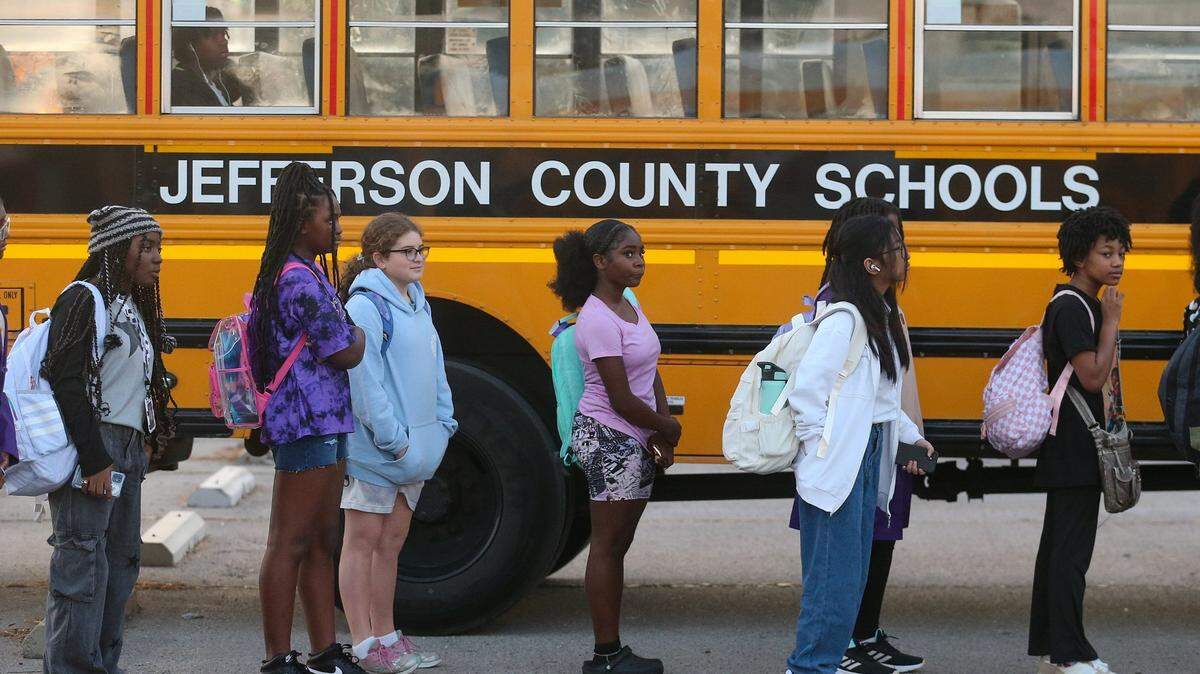 Jefferson County Public School students stand beside their bus as they prepare to transfer buses on Friday, August 18, 2023. JCPS had to rethink their strategy after the first day of school saw students arriving home late. Some close to 10pm.