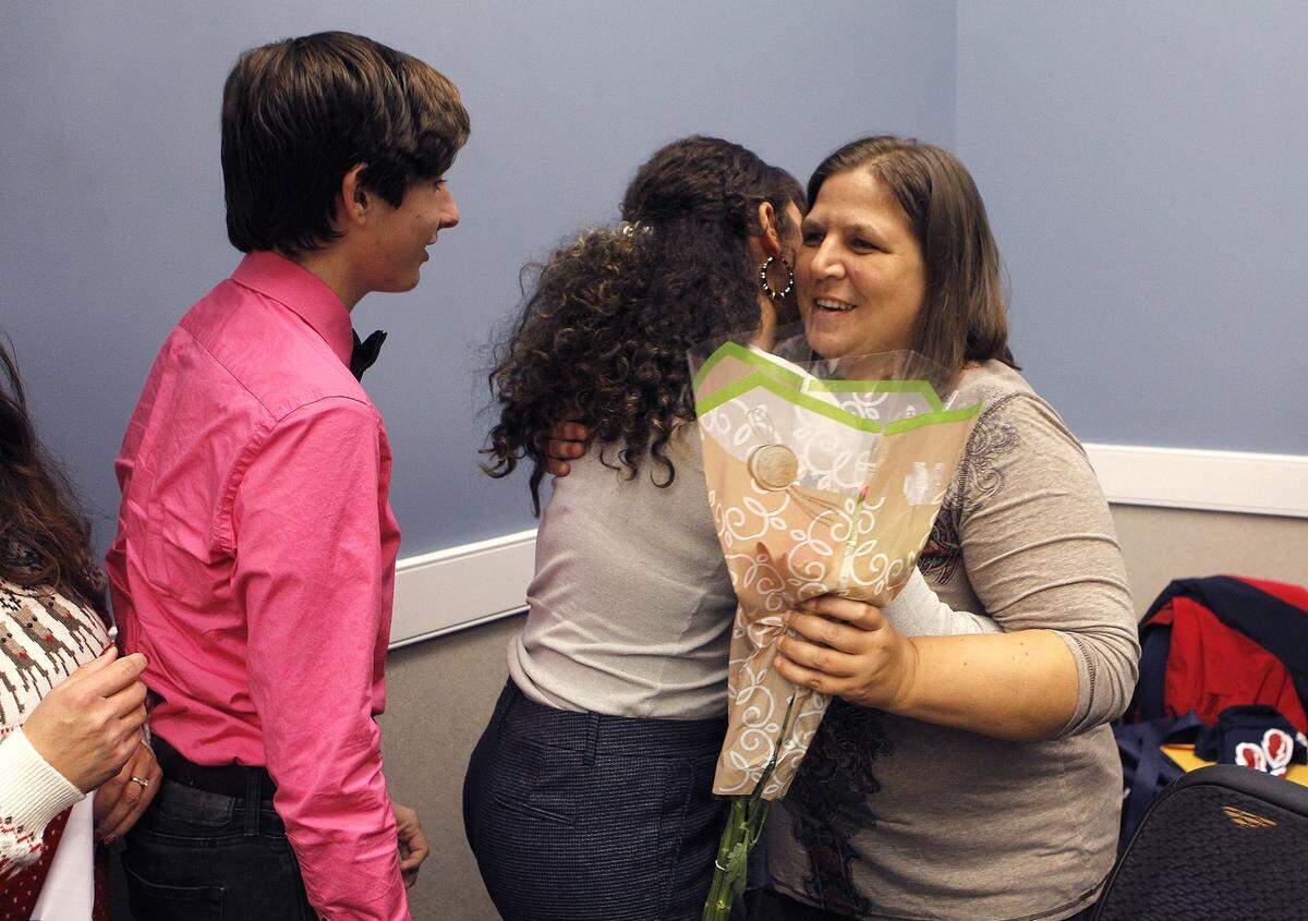 Colin Dulaney, left, watched as fellow student Kimberly Legel hugged Koeberle Bull, who helped thwart a possible school shooting in Kentucky. Bull, a Lumberton, N.J., widow, and her three children — Olivia, 16, Sophia, 11, and Isaiah, who just turned 9 — were feted by a crowd of citizens in a stop in December at the Anderson County School District offices.