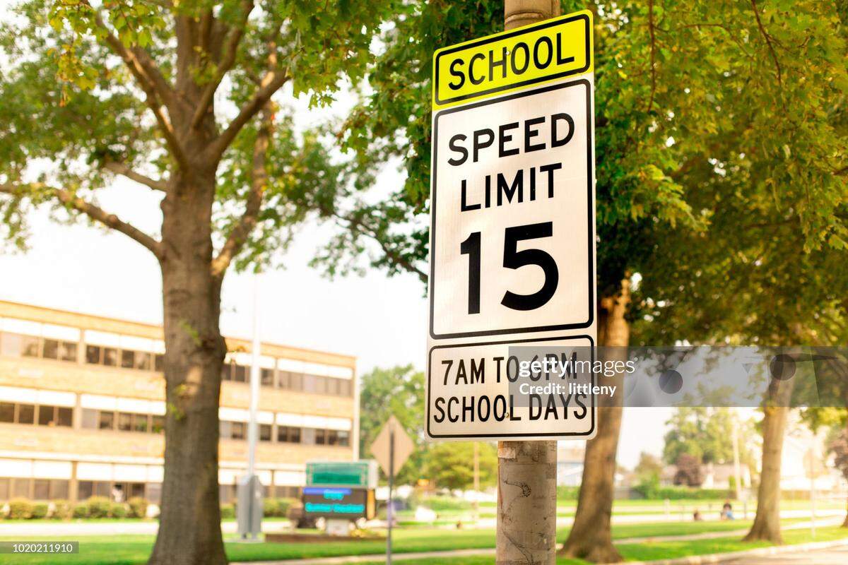 This stock image shows a sign indicating a school zone speed limit of 15 miles per hour. 