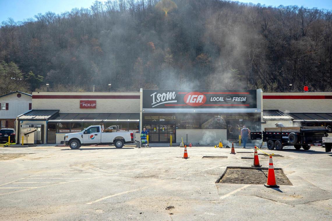 Crews work to patch asphalt in the parking lot of Isom IGA on Thursday.