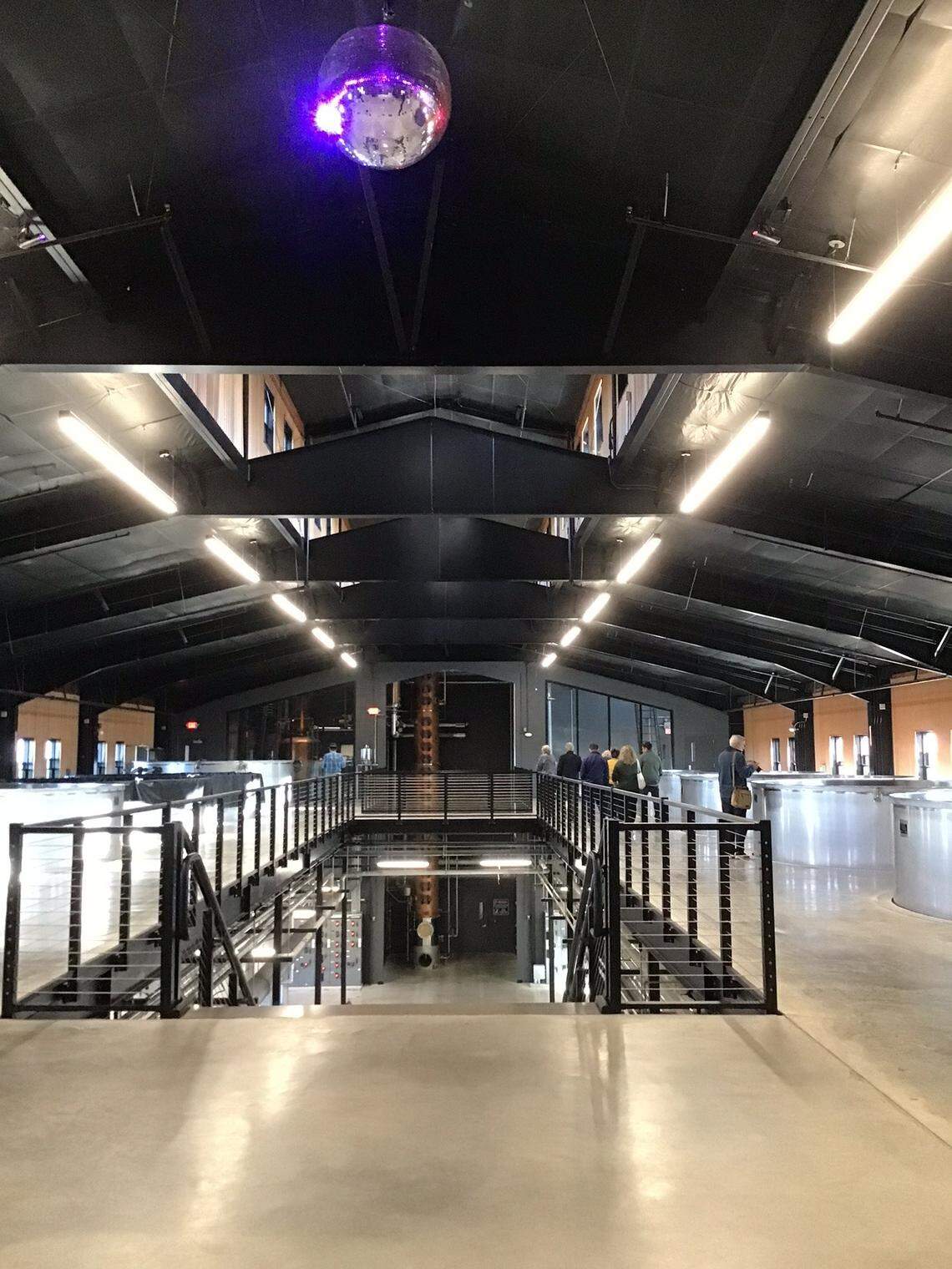 A disco ball under colored spotlights hangs overhead in the Potter Jane Distillery. Co-founder Denny Potter sometimes roller skates around the fermentation tanks on the side or on his way to and from the still in the background.