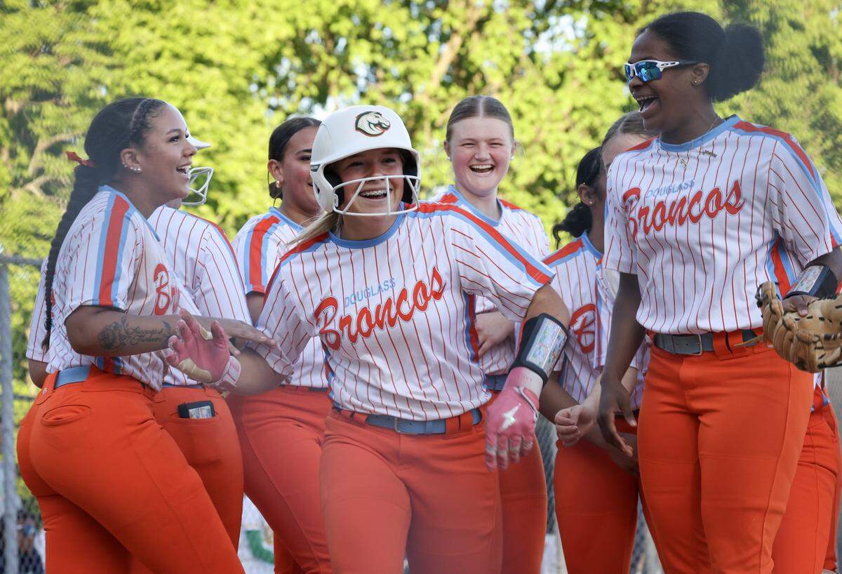 Frederick Douglass softball’s Savannah Wombles, center, and her teammates celebrate her scoring the winning run in the seventh inning against host Bryan Station on May 9.