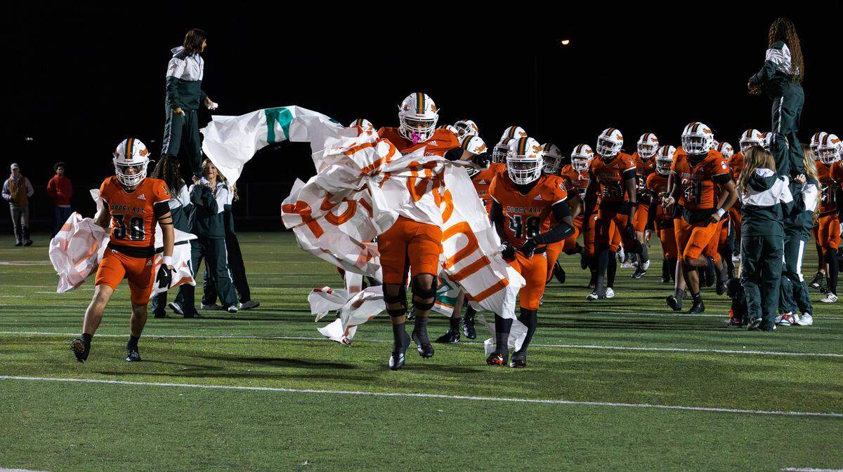 Frederick Douglass players burst through their school banner before the Class 6A second round playoff game between the Bryan Station Defenders and the Broncos on Nov. 14. A new playoff format is being considered for first- and second-round games.
