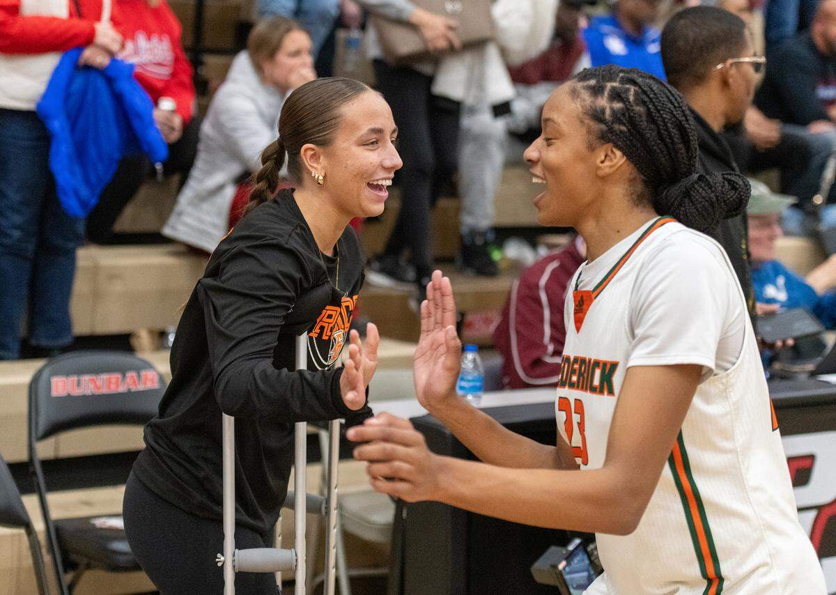 Frederick Douglass senior Kate Baker, left, greets teammate Jaelee Knowles at Saturday night’s 11th Region Tournament championship game. Baker is out for the season after tearing the ACL in her right knee late in February.