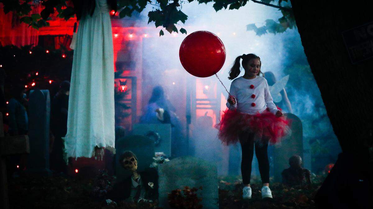 Kendall Pugh, 11, of Lexington, Ky., dressed as Pennywise from the movie “It” stands in her grandparent’s yard waiting for trick-or-treaters in Lexington, Saturday, Oct. 31, 2020.