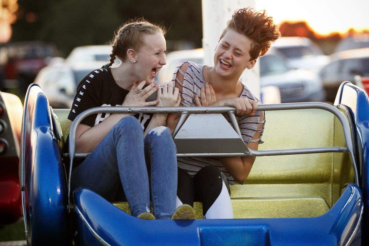 Jessica Shumate, 13, of Lancaster, left, and Haley Anderson, 13, of Danville, laugh while riding the Sizzlerat the Garrard County Fair in Lancaster, Tuesday, June 25, 2019.