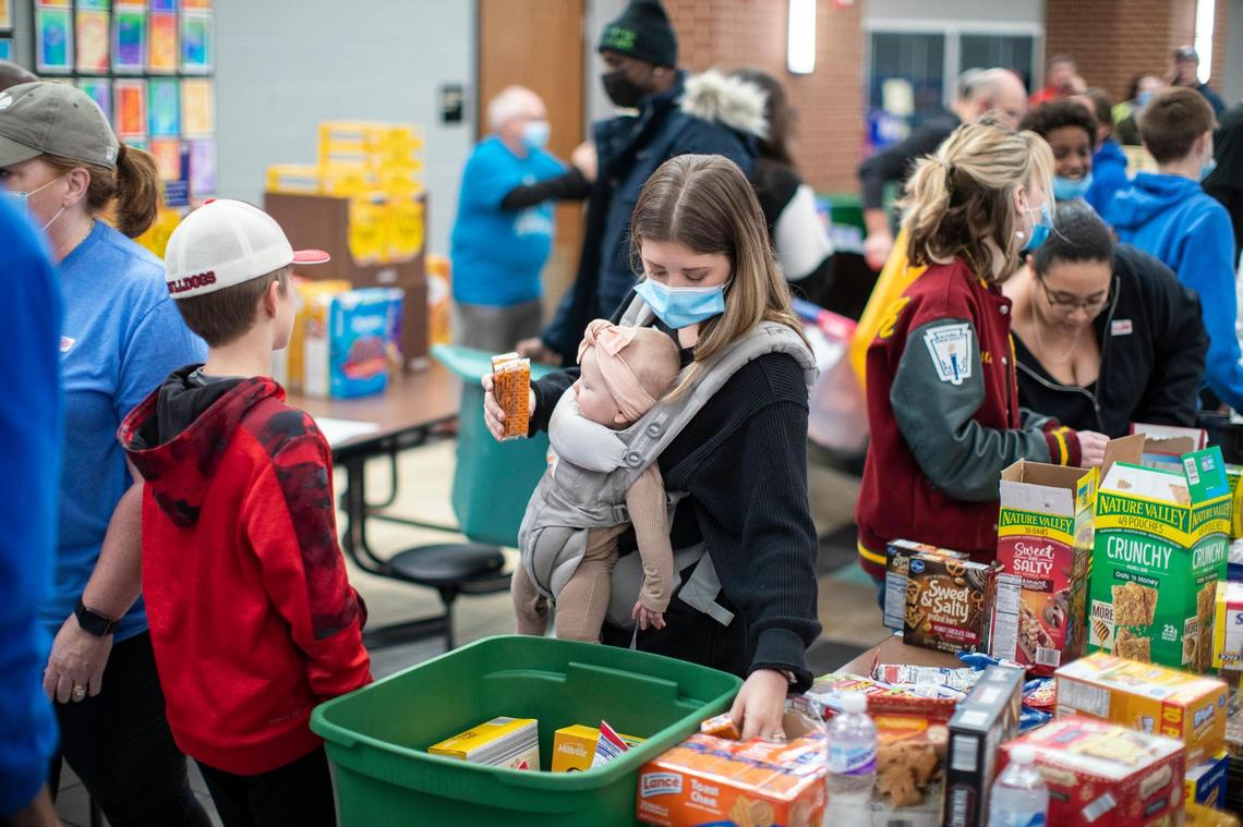 Volunteer Molly Westbook, carrying her baby Riley, helps sort and gather essential supplies at South Warren High School Sunday.