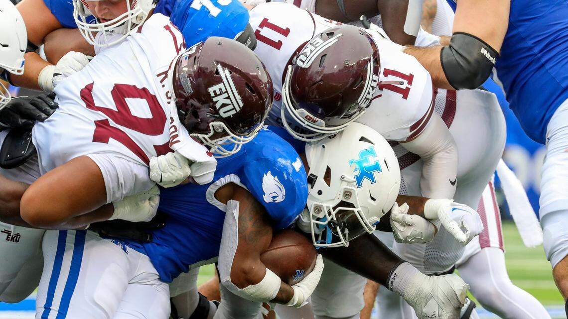 Kentucky running back Ray Davis (1) is tackled by Eastern Kentucky defensive lineman Ryan Jackson (97) and linebacker Logan Blake (11) during Saturday’s game at Kroger Field.