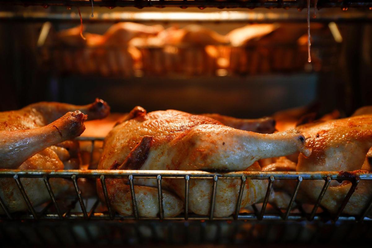 Rotisserie chickens cook May 12 at Rosticeria Doña Coco in Lexington. Each chicken is injected with garlic butter and seasoned with olive oil, ginger, salt, pepper and paprika before roasting.
