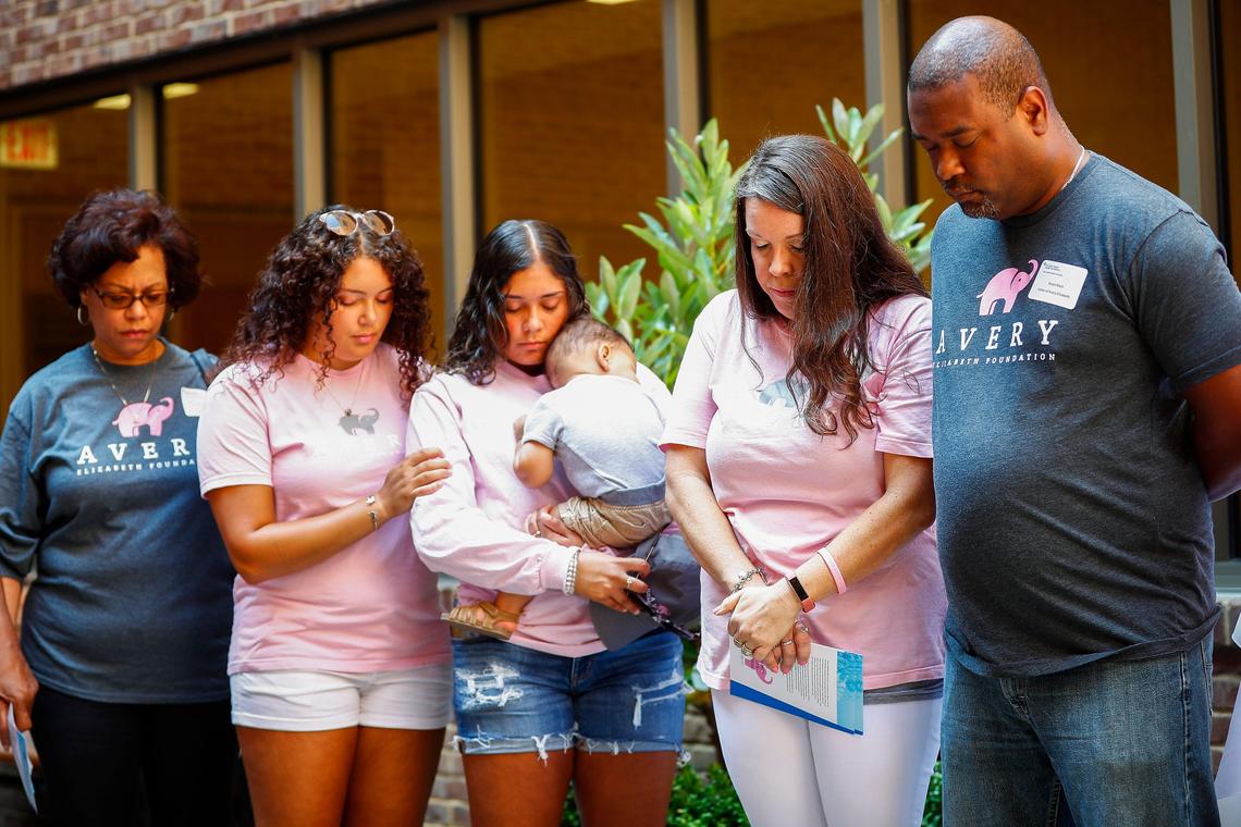 Relatives of Avery Elizabeth Black, grandmother Tolora Hale, from left, siblings Tahlia Black, Arianna Black, and Marshall Black, and parents Katie Black and Bryan Black, all of Lexington, Ky., bow their heads in prayer during a memorial sculpture unveiling ceremony for Avery in the courtyard at the Women’s Hospital at Saint Joseph East in Lexington, Ky., Saturday, July 27, 2019. Avery Elizabeth Black was stillborn two years ago on July 27, 2017.