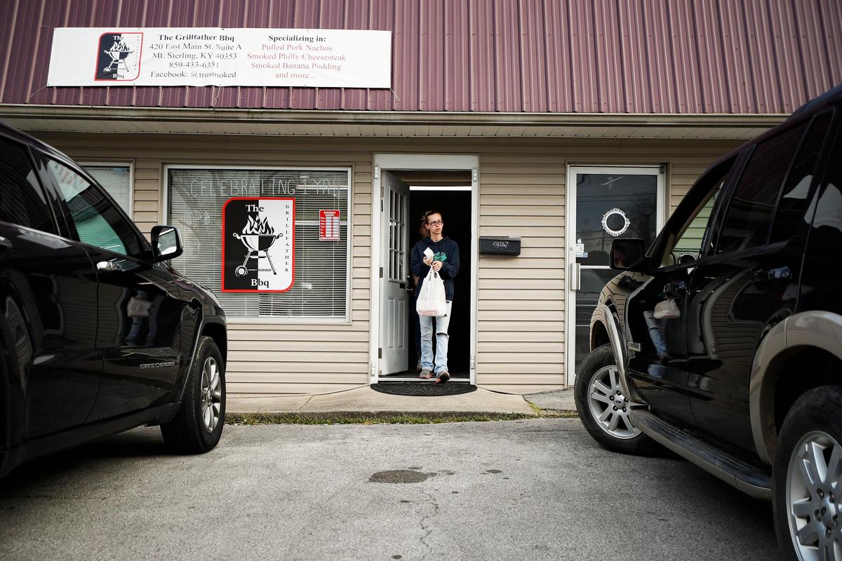 Jenny Lawhorn delivers a takeout order Wednesday to a customer in the parking lot at The Grillfather.