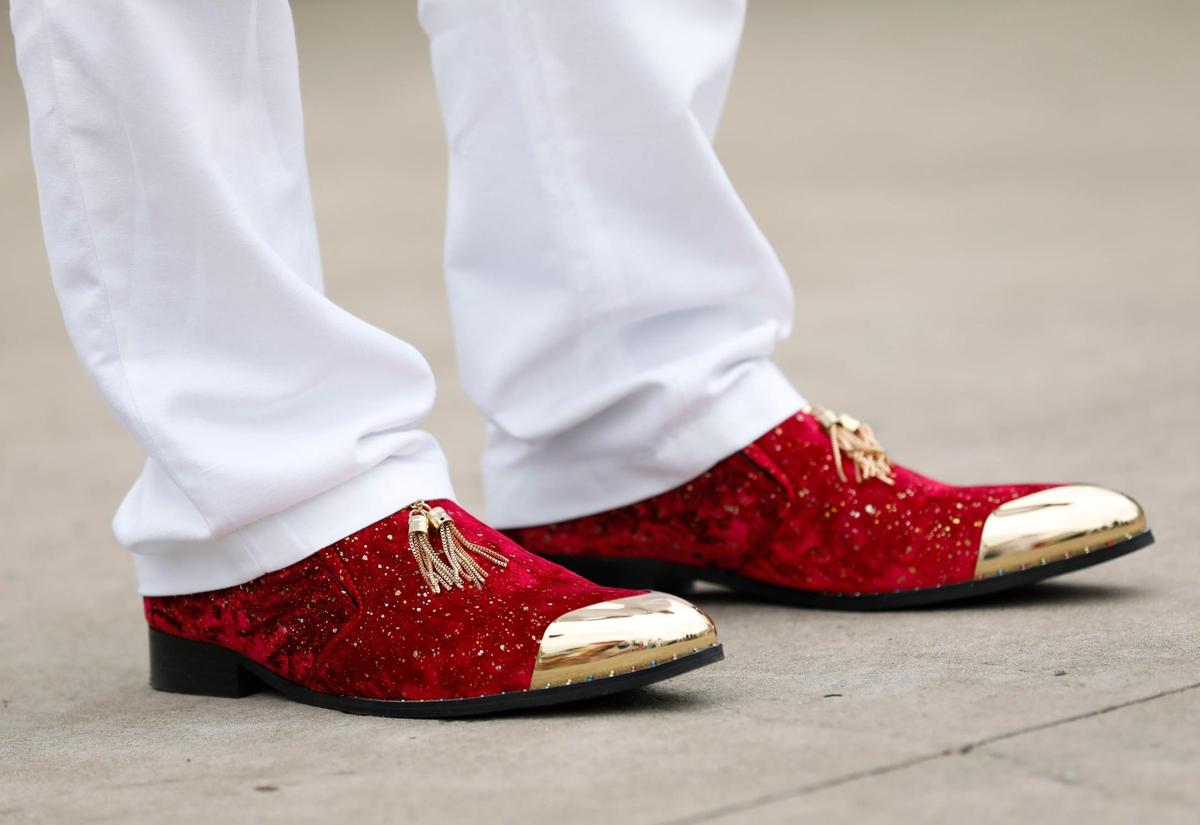 Steven Tunnell wears velvet red and gold shoes to match his suit jacket with a print of red roses by Loudmouth at Churchill Downs in Louisville, Ky., Saturday, May 7, 2022.