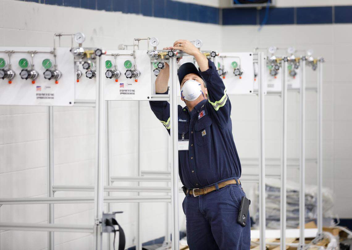 Workers put together oxygen manifolds for use in a temporary hospital set up inside UK’s Nutter Field House, which is normally used for athletics.