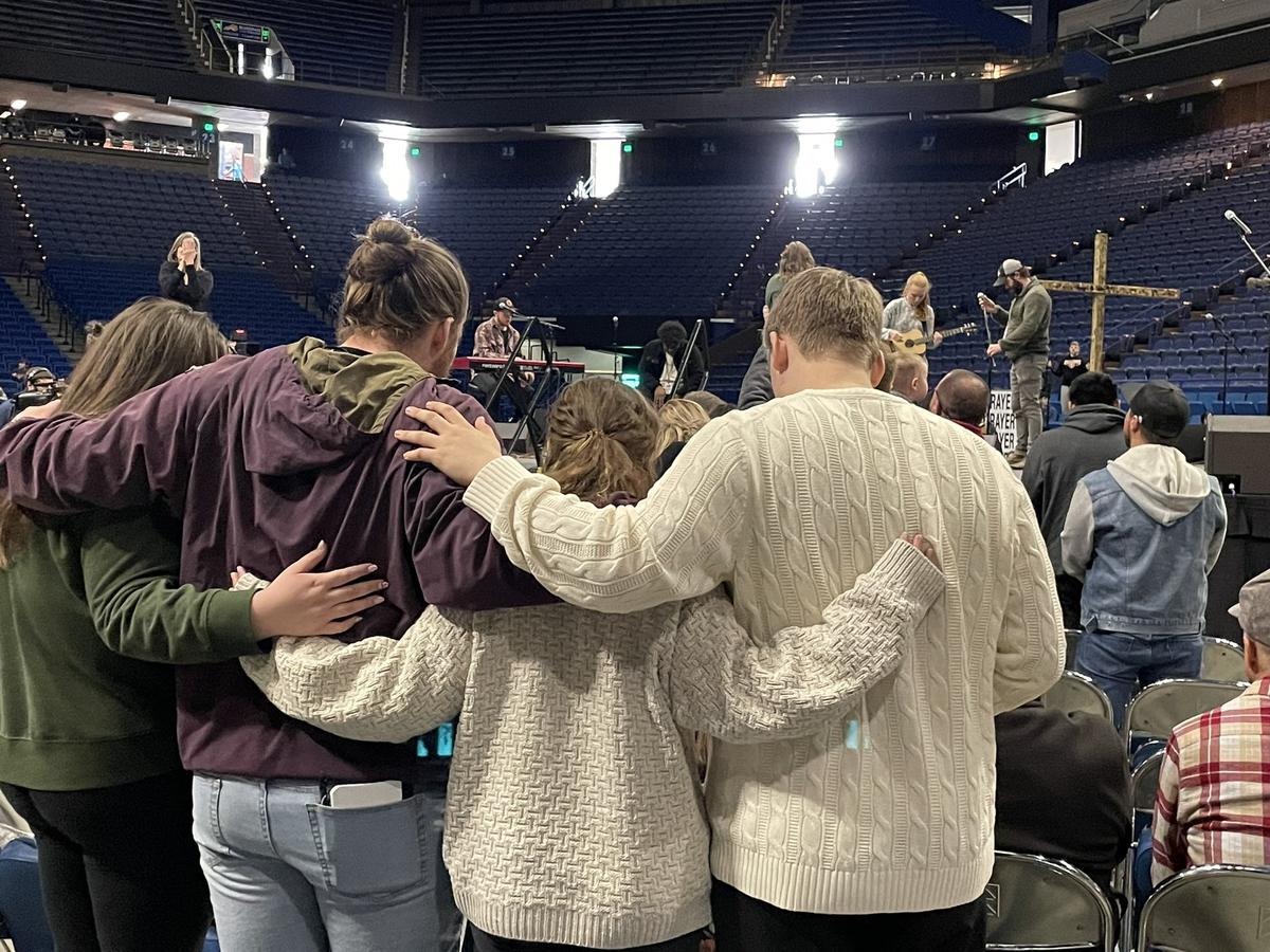 A group leans on each other during worship at Rupp Arena. 