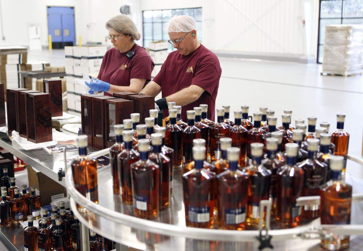 Charlene Dillow, left, and Ron Bennett, right, place bottles in wooden boxes as Wild Turkey Diamond is bottled at the distillery located on U.S. 62 at the Kentucky River near  Lawrenceburg, Ky., Friday, April 11, 2014. 