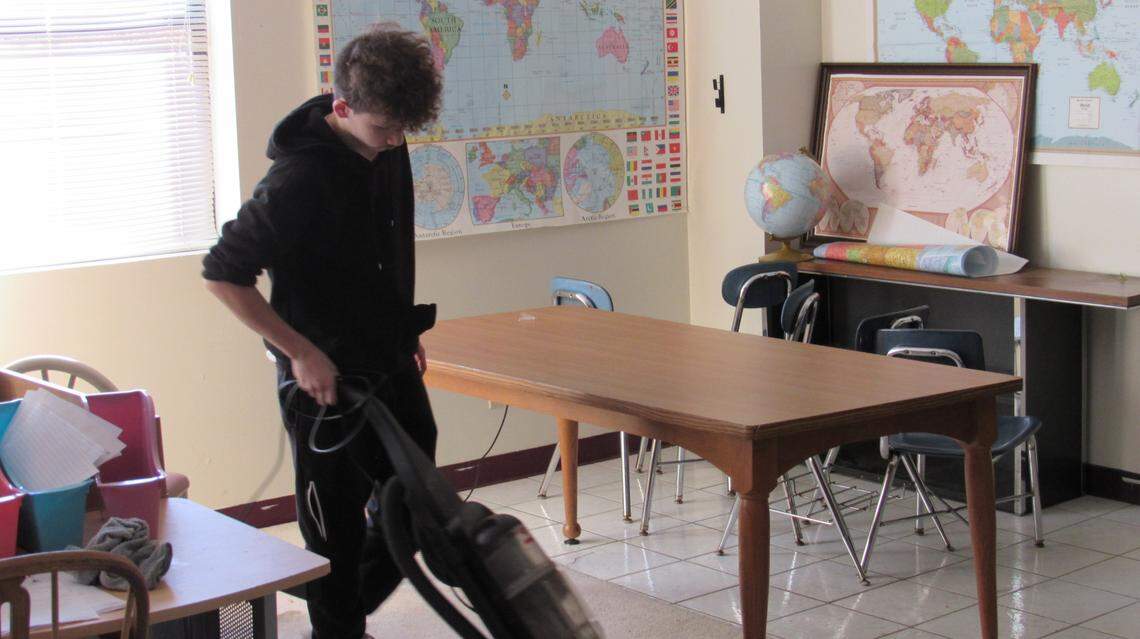 Brayden Johnson, 15, vacuums a classroom at the David School on Dec. 6, 2024. Students at the school for kids at risk of dropping out help with chores.