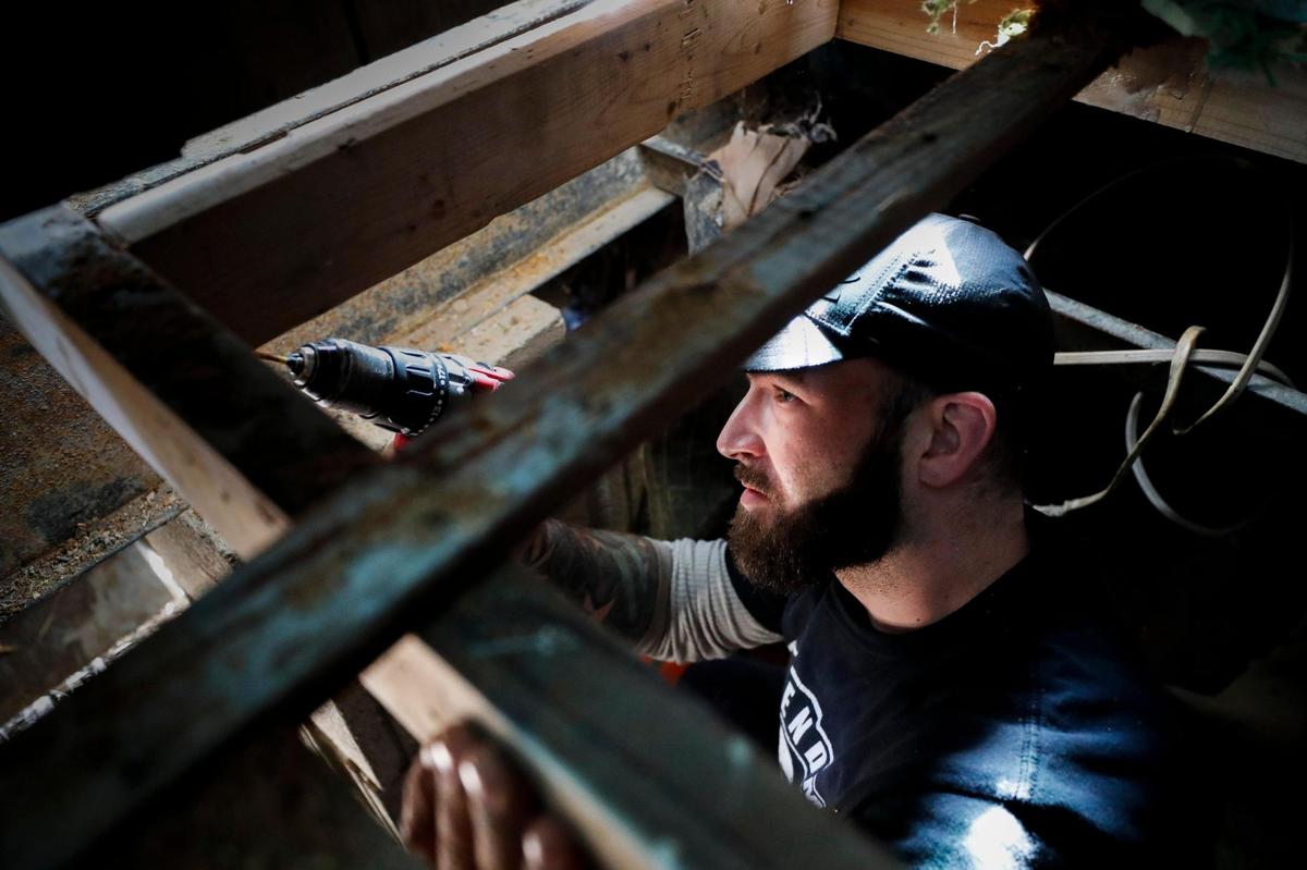 KJ Jude, of Chattaroy, W. Va., works to repair floorboards in the Smith trailer following the Big Creek flood in Sidney, Ky., Thursday, Jan. 13, 2022.