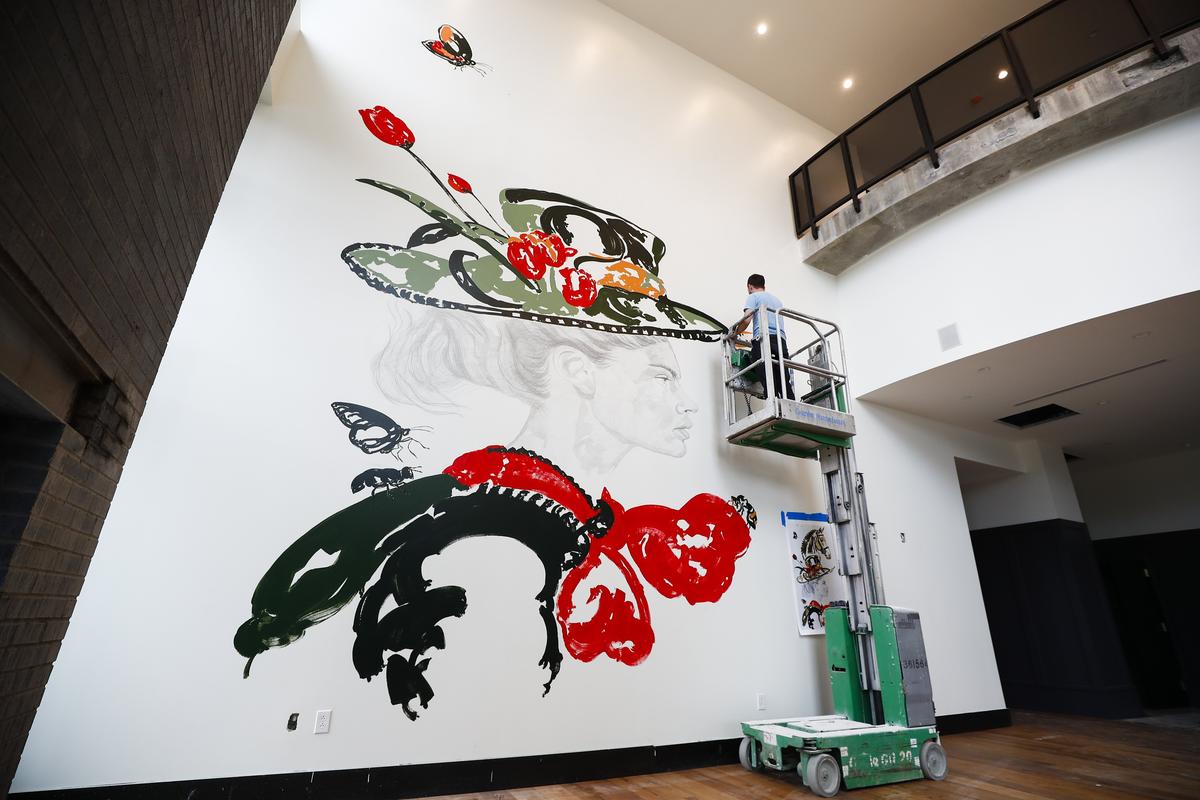 Muralist Carlos Gamez de Francisco works on the mural overlooking the lobby at the new Origin Hotel.