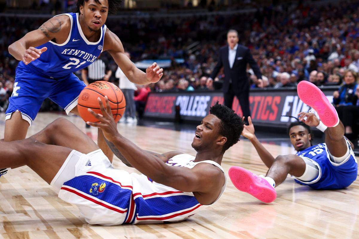 Kentucky guards D.J. Wagner (21) and Antonio Reeves (12) dive for a loose ball against Kansas forward K.J. Adams Jr. (24) during the State Farm Champions Classic at the United Center in Chicago.