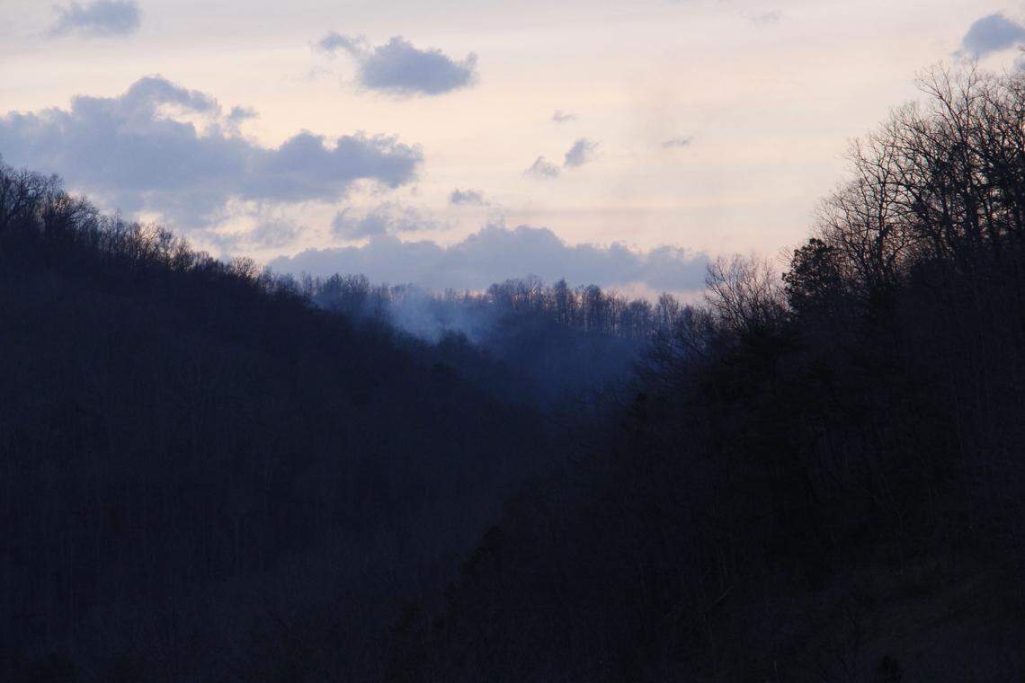 Wildfire smoke lingers in a valley during the early evening hours March 31, 2026, in rural Knott County northeast of the small community of Vest.