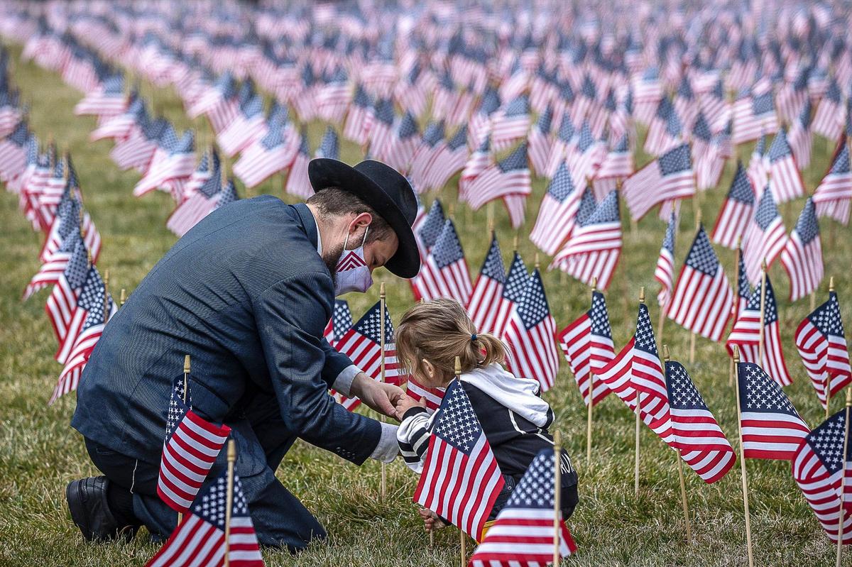 Rabbi Shlomo Litvin, Chabad of the Bluegrass director, and his son, Kehos, 2, both of Lexington, place flags Feb. 4 on the back lawn of the Kentucky state Capitol in honor of Kentuckians who have died from complications from COVID-19.