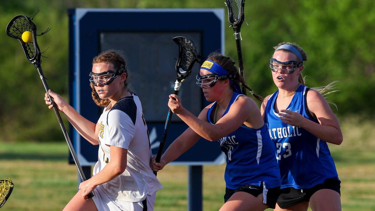 Sayre’s Izzy Brogden (21), left, operates against the Lexington Catholic defense of Audrey Stack (16) and Lily Hester (23) during a Commonwealth Lacrosse League regional finals game at Sayre on Monday. Sayre won 13-12.