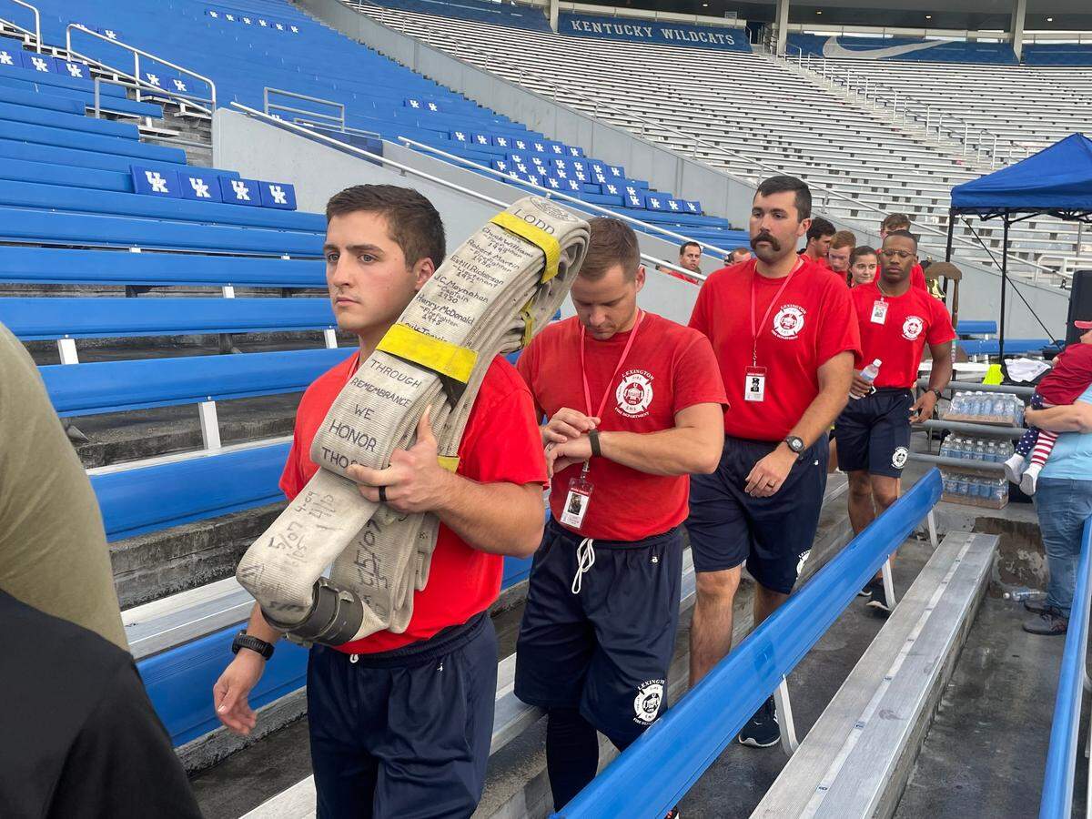 Lexington Fire recruits trade off holding a fire hose with the names of all the fallen firefighters.