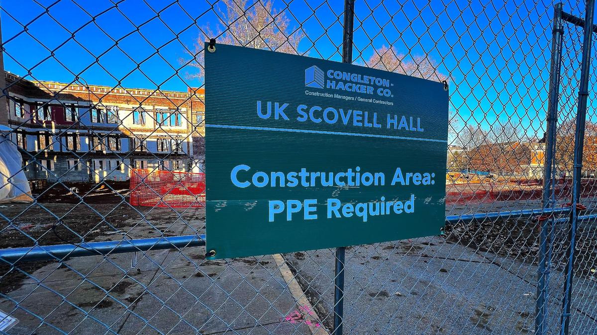 A UK Scovell Hall sign hangs on a secure construction fence, stating onsite protective gear requirements on December 7, 2024, in Lexington, Ky.