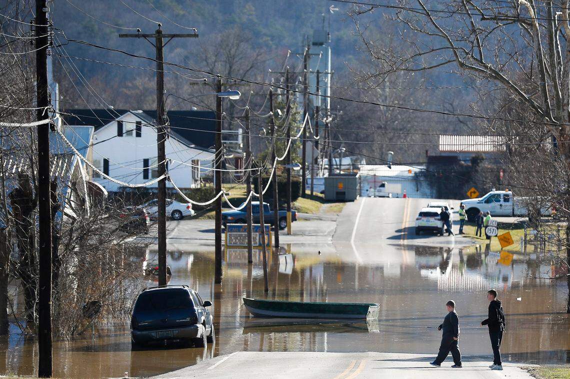People walk near a flooded Ky. 52 following heavy rains that caused the Kentucky River to flood in Ravenna, Ky., Tuesday, March 2, 2021.