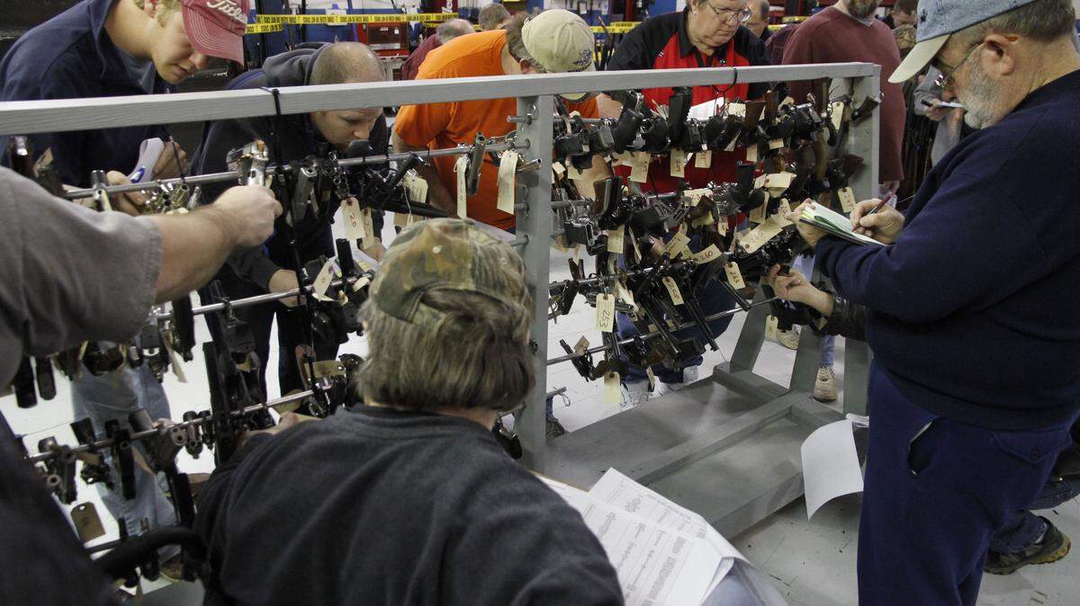 Prospective bidders examined handguns Tuesday at an auction of guns confiscated by police and sheriff's departments in the state. Proceeds go toward protective equipment and weapons.  