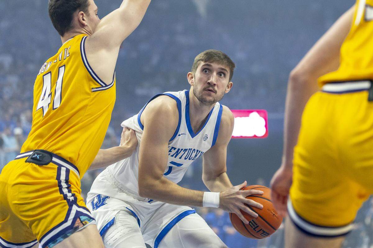 Kentucky forward Andrew Carr (7) looks to move the ball as Lipscomb forward Jacob Ognacevic (41) defends.