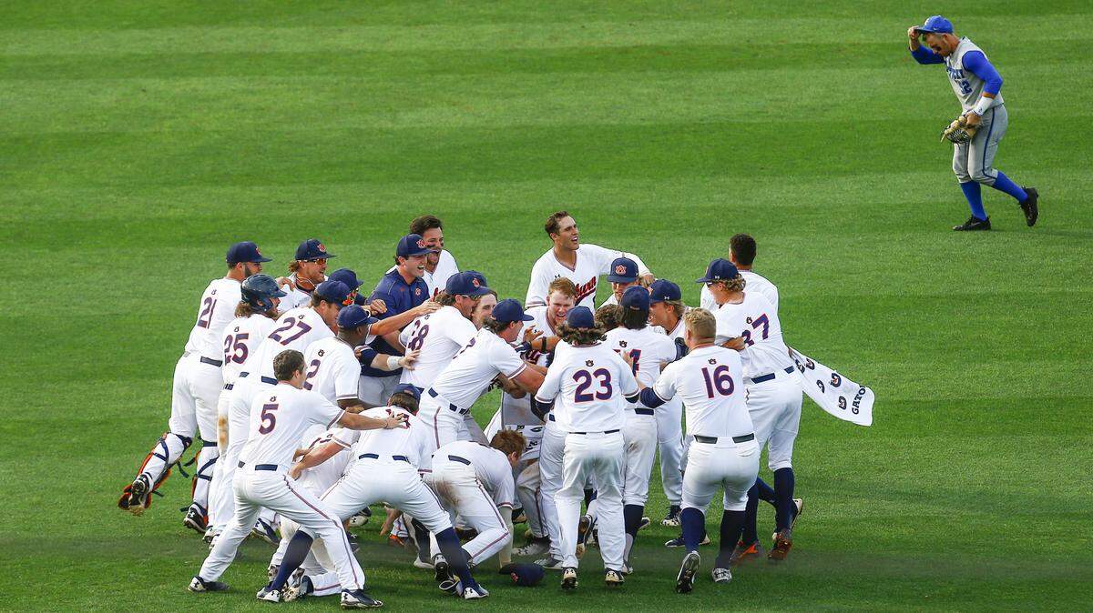 Kentucky outfielder Ben Aklinski jogged off the field as Auburn players celebrated their win with Edouard Julien (10) after he drove in the winning run during the 11th inning in Hoover, Ala., on Tuesday.