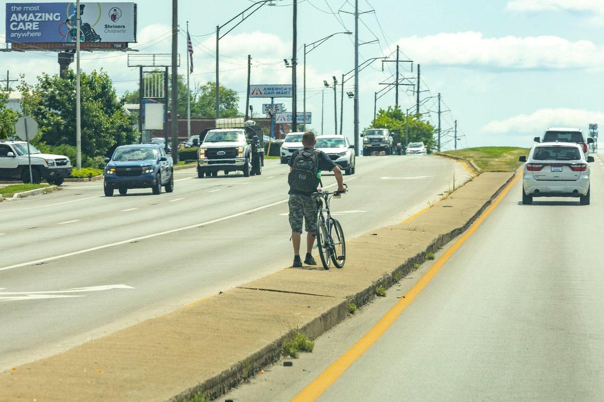 A person attempts to cross New Circle Road in Lexington, Ky., on Monday, Aug. 12, 2024.